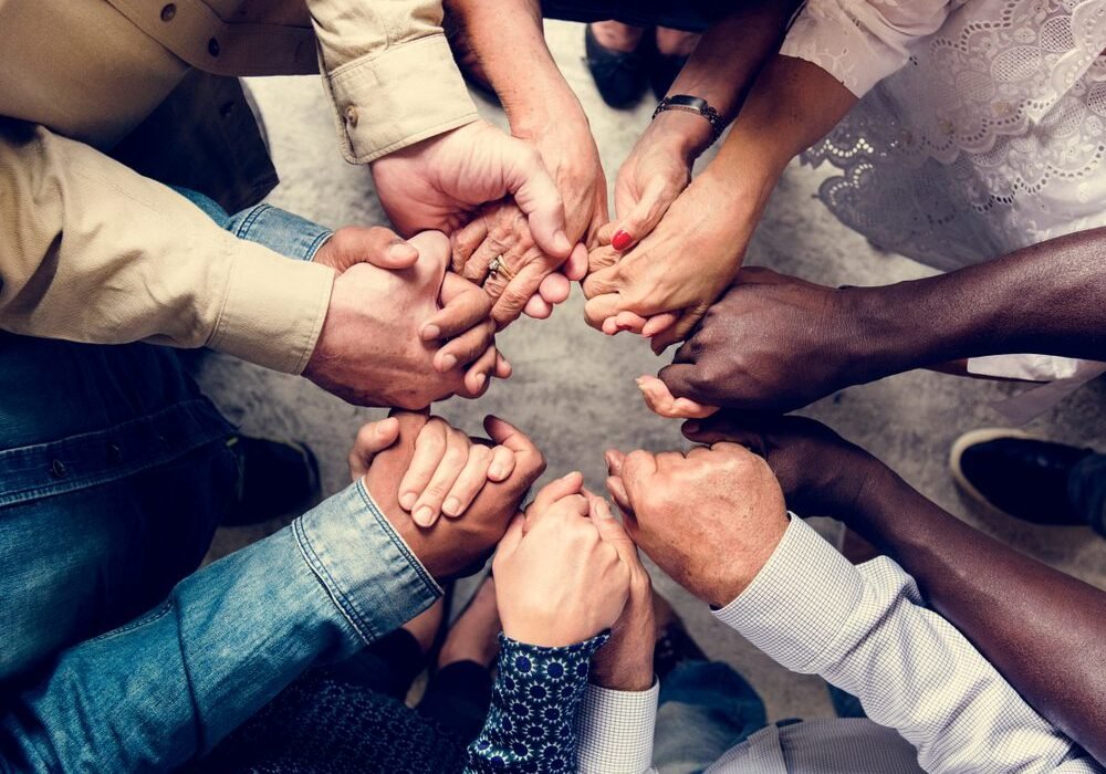 Group of diverse hands holding each other support together teamwork aerial view